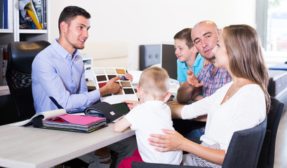 Obraz premium Handsome salesman in furniture store helping young family in choice