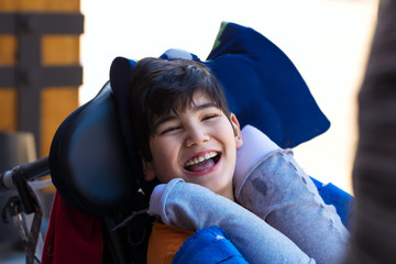 Biracial eleven year old boy in wheelchair outdoors, smiling