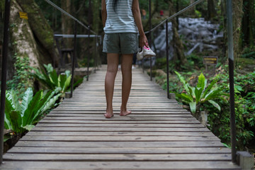 Thai women barefoot walking on wood bridge.