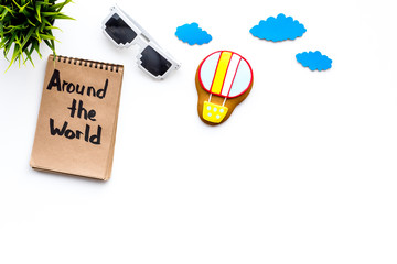 Family trip concept. Air balloon cookie, sun glasses. Around the world hand lettering in notebook on white background top view copy space