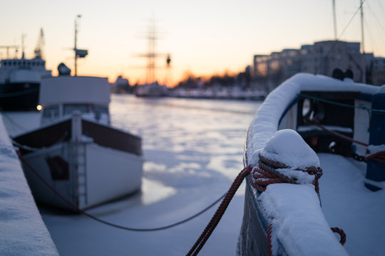 Selective focus on mooring bollard on boat covered by snow during winter sunset