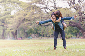 Asian couple lovers under a vast field of nature in a park.