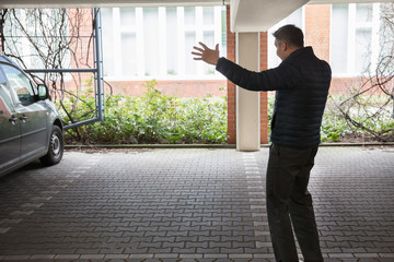 Rear View Of A Shocked Man Standing In Parking Lot