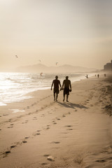 Silhouette of two friends walking on the beach during sunset