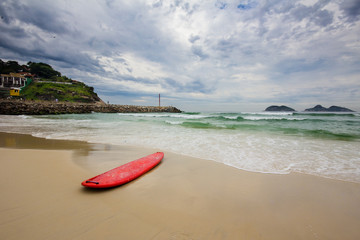red surfboard laying on shorebreak
