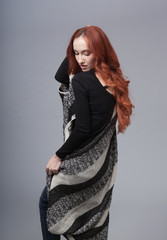 Fototapeta premium Portrait of a beautiful girl with long red hair on a gray background in the studio