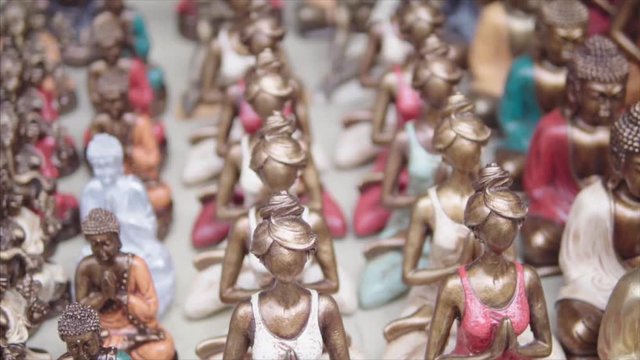 Statue souvenirs of women in yoga pose during the meditation. Camera is slowly going along the line of figures