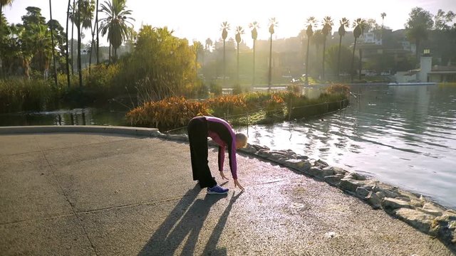 71 year old woman stretching after her morining walk in the park.