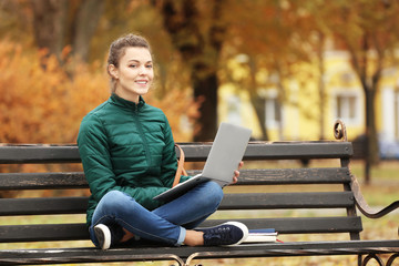 Obraz premium Teenage girl with laptop studying in park