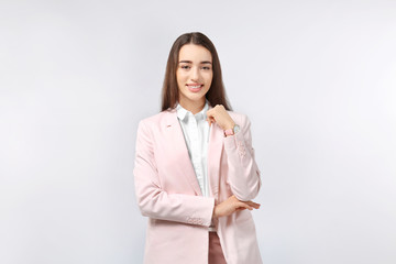 Beautiful young woman in elegant suit on light background