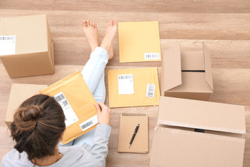 Female startupper preparing parcels for shipment to customers indoors