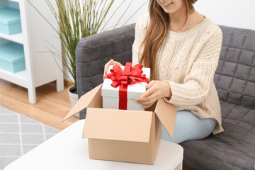Woman taking gift box out of parcel at home