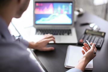 Man working at table in office, closeup. Financial trading concept