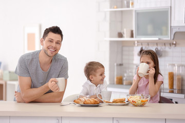 Father with children having breakfast in kitchen