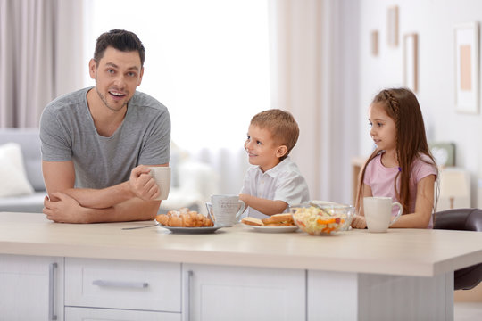 Father with children having breakfast in kitchen