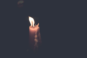 One yellow candle burning brightly in black background