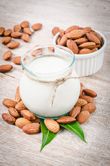 Almond milk and dry almond nuts with green leaf.