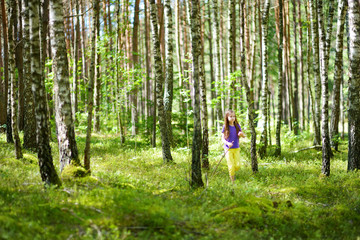 Cute little girl having fun during forest hike on beautiful summer day