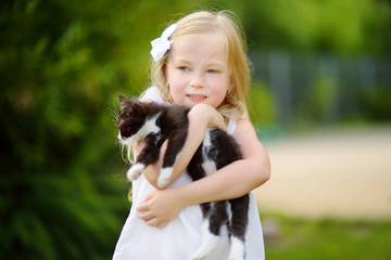 Cute little girl with her pet kitten on warm summer day. Kids and animals.