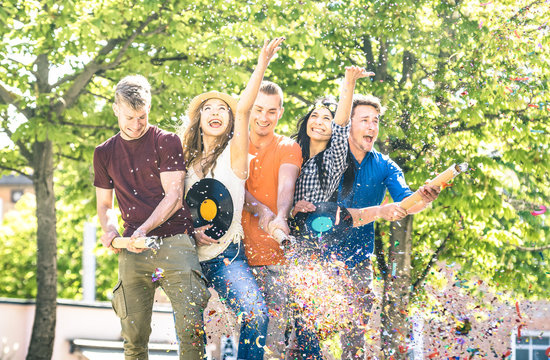 Group of happy excited friends having fun outdoor cheering with confetti - Young people enjoying spring summer time together at garden party - Youth friendship concept on warm afternoon color filter
