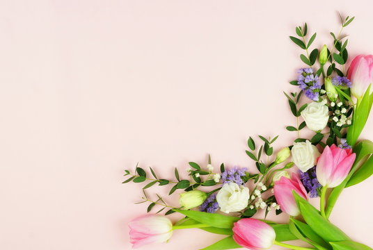 Frame of flowers and eucalyptus branches on a pale pink background.Holiday concept. Copy space. Top view
