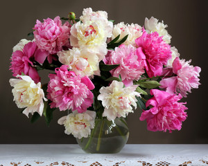 Peonies in a jug on the table. Bouquet of garden flowers.