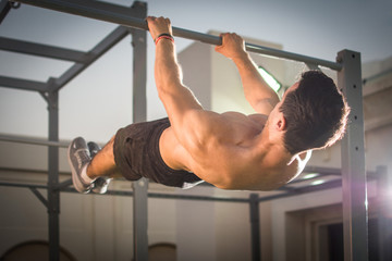 Handsome muscular man doing exercises on horizontal bar outdoors. Calisthenics workout. - obrazy, fototapety, plakaty