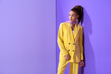 african american girl posing in yellow suit, on trendy ultra violet background