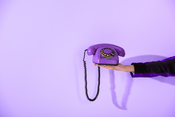 cropped view of girl holding vintage rotary phone at ultra violet wall