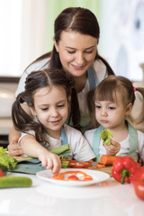 Cute mom and her kids making vegetable salad