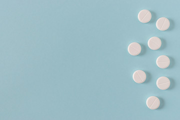 White pills on the bright blue surface. Top view.