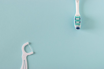 Toothbrush and dental floss on bright blue background.