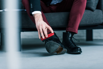 partial view of businessman cleaning stylish black shoes
