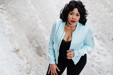 Stylish african american plus size model at streets of city on winter day.