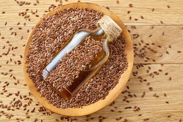 Top view closeup picture flax seeds and linseed oil in a glass bottle on a wooden background, shallow depth of field.