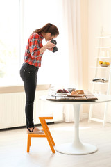 Young woman with professional camera taking still life pictures indoors