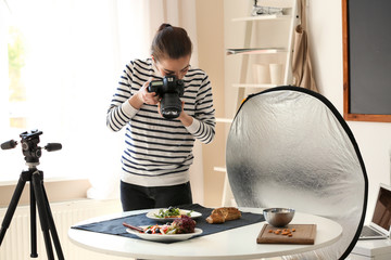 Young woman with professional camera taking still life pictures indoors