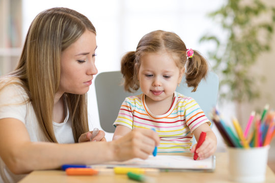 Kindergarten teacher and kid girl drawing lessons at school