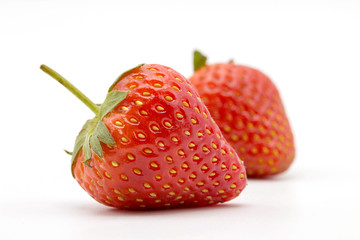 Two strawberries close up on white background.