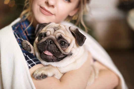 Young woman with cute pug dog at home. Pet adoption