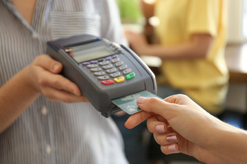 Woman using bank terminal for credit card payment in cafe