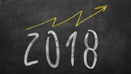 optimistic year graph drawn on the blackboard. handwritten 2018 year inscription with growing yellow arrow