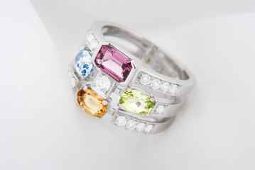 White gold ring with citrine peridot, blue topaz, pink tourmaline and diamonds on soft white background