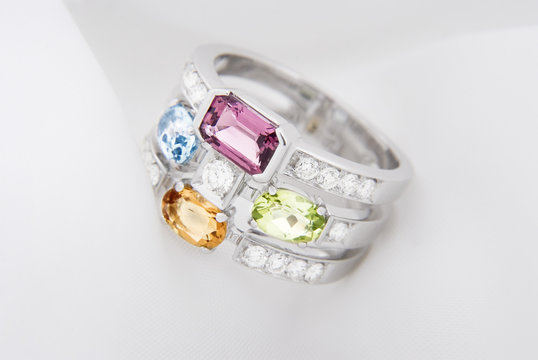White gold ring with citrine peridot, blue topaz, pink tourmaline and diamonds on soft white background