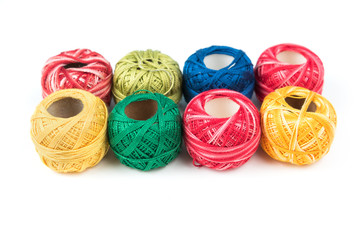 Set of eight colourful sewing threads on a white background