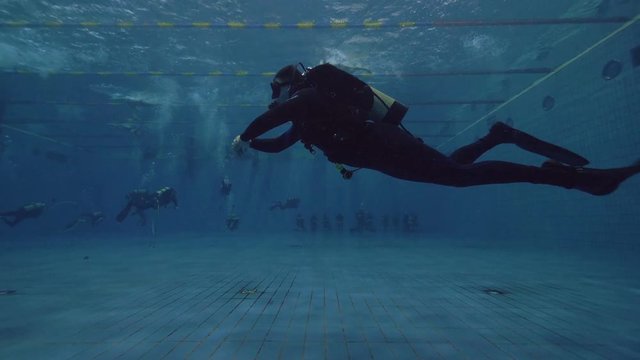 Scuba diver floating underwater in swimming pool. Learning scuba diving course