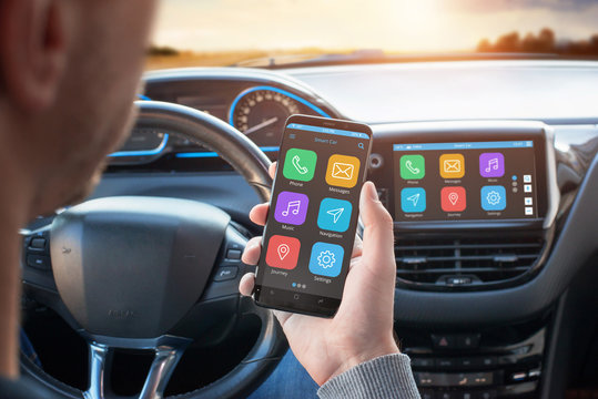 Driver uses a mobile phone with smart driving assistance apps. The app is connected to a car computer and is displayed on the board display. - Powered by Adobe