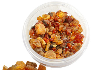 Amber of different color, size and shape. Beautiful composition with amber in a glass jar on a white background. Sun stone in different forms. Group of jewelry stones. Stone natural mineral color 