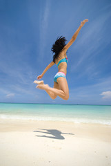Fototapeta na wymiar asian girl jumping in joy on a beach