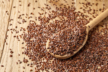 Wooden spoon with flax seeds on rustic background, top view, close-up, shallow depth of field, selective focus